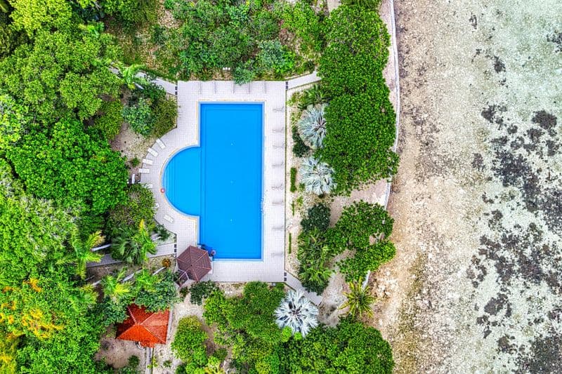Aerial drone view of a tropical resort swimming pool directly at the Indonesian coastline