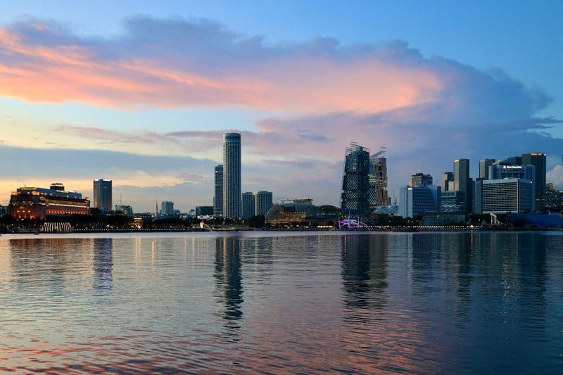 Singapore downtown skyline reflected in Marina Bay waters at dusk, viewed from the waterfront
