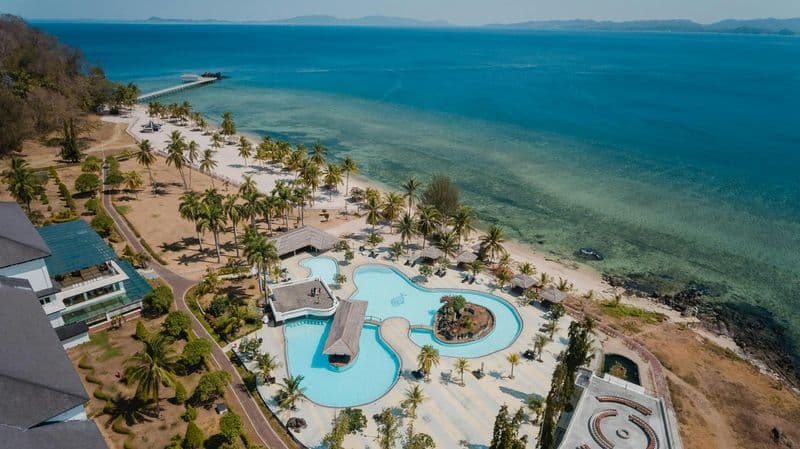 Aerial drone photograph of an Indonesian beachfront resort with pool and palm trees